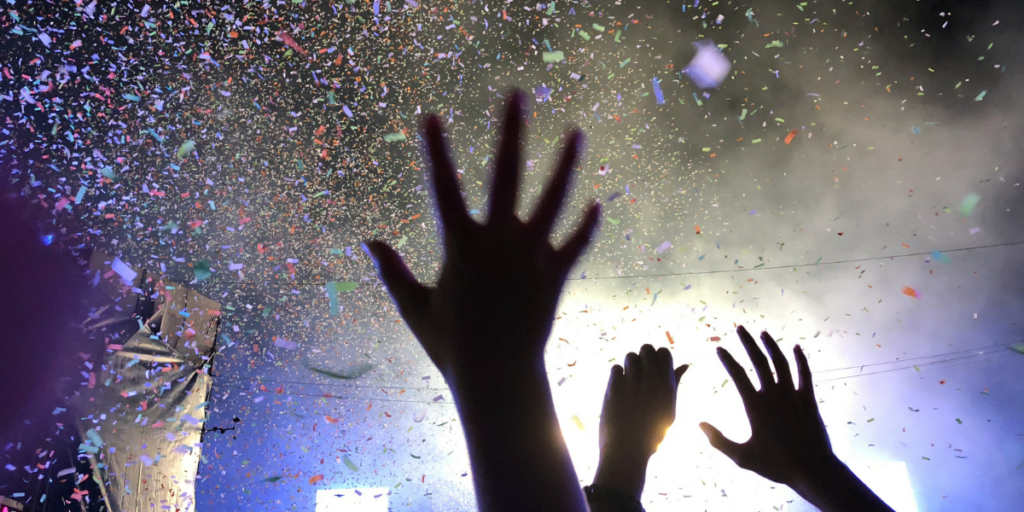 immagine concettuale concerto - mani in aria, luci e corandoli
