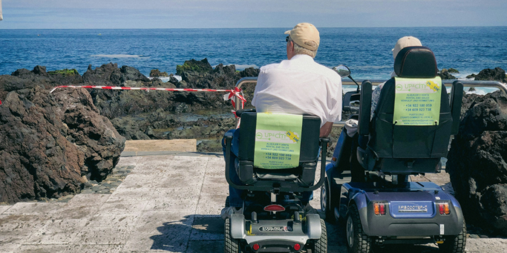 due persone su carrozzine motorizzate guardano il mare e si rilassano